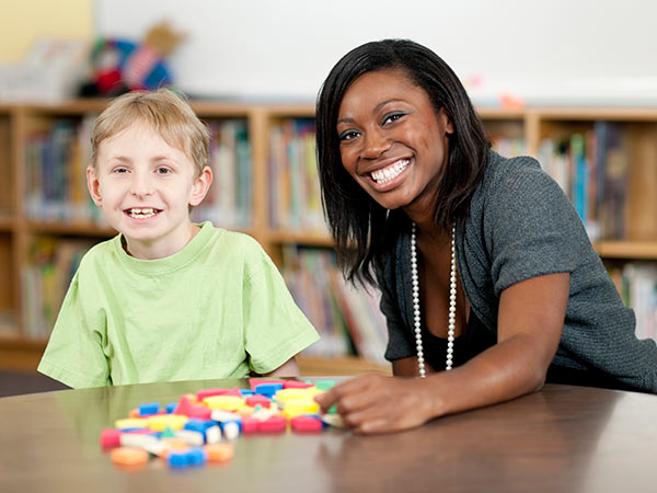 女人和孩子微笑着与彩色的形状在桌子上。